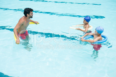 Coach and students interacting with each other in swimming pool