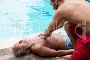 Lifeguard pressing chest of unconscious senior man