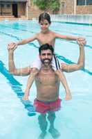 Father carrying son on shoulder in pool