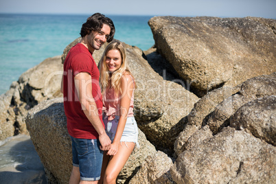 Portrait of romantic couple by rock formations at beach