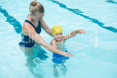 Female instructor training young boy in pool