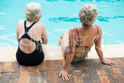 Two senior women sitting together at poolside