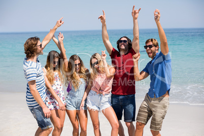 Young friends dancing at beach during sunny day