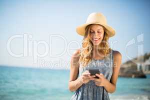 Woman smiling while using mobile phone at beach