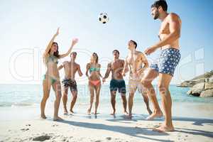 Happy friends playing soccer at beach