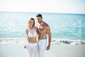 Portrait of couple standing with arm around on shore