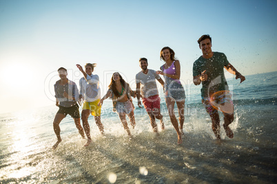 Friends running on shore at beach