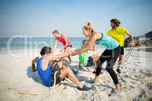 Friends helping man and woman while playing tug of war
