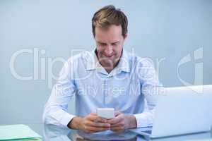 Smiling doctor using mobile phone