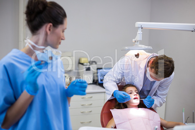 Dentist examining a young patient with tools