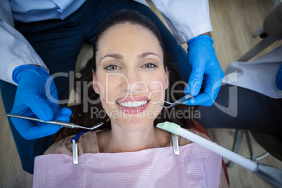 Dentist examining a female patient with tools