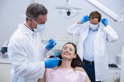 Dentist examining a female patient with tools