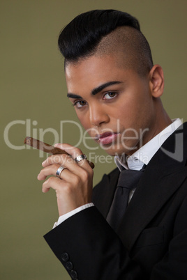 Transgender woman holding cigarette on green background