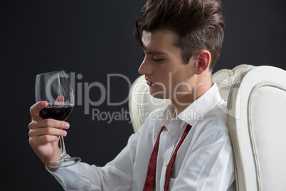 Thoughtful androgynous man holding wine glass