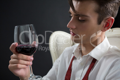 Thoughtful androgynous man holding wine glass