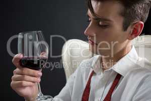 Thoughtful androgynous man holding wine glass