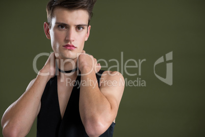 Androgynous man in waistcoat posing against green background