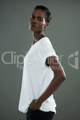 Androgynous man in white top posing against grey background