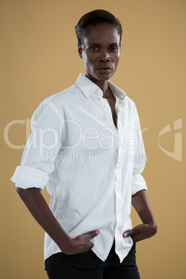 Androgynous man in white shirt posing against beige background