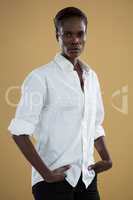 Androgynous man in white shirt posing against beige background