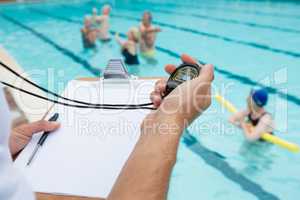 Swim coach looking at stopwatch near poolside