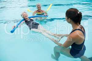 Female coach helping senior women in swimming pool
