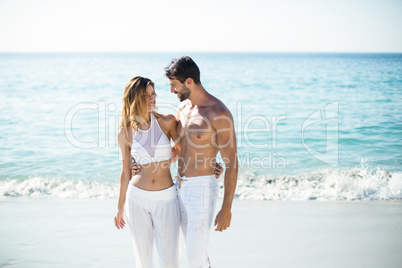 Young couple standing with arm around on shore