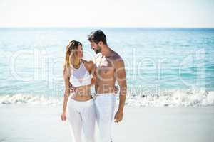 Young couple standing with arm around on shore