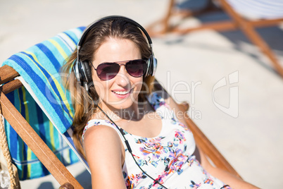 Young woman listening songs while relaxing on deck chair