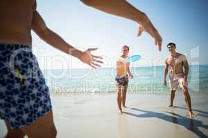 Male friends playing frisbee on shore