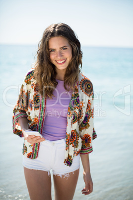 Young woman smiling while standing on seashore