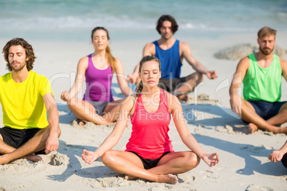 Friends meditating in lotus position on shore