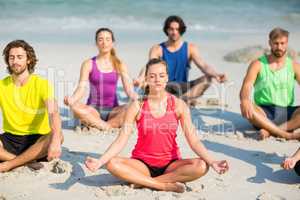 Friends meditating in lotus position on shore