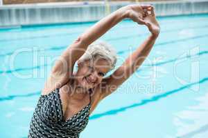 Smiling senior woman exercising at poolside