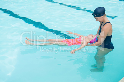 Female instructor training young girl in pool