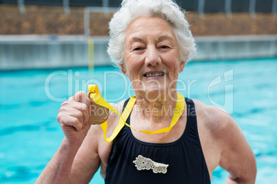 Senior woman showing gold medal at poolside