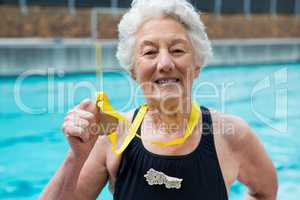 Senior woman showing gold medal at poolside