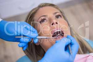 Dentist examining a female patient with tools