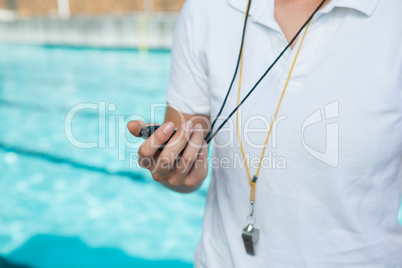 Female coach holding stopwatch at poolside