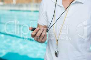 Female coach holding stopwatch at poolside