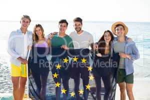 Friends holding European Union flag on shore at beach