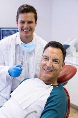 Portrait of dentist examining a male patient with tools