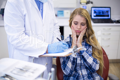 Dentist preparing dental report of female patient