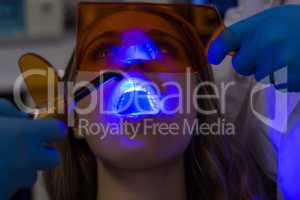 Dentists examining female patient with dental curing light