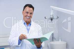 Portrait of smiling dentist holding file