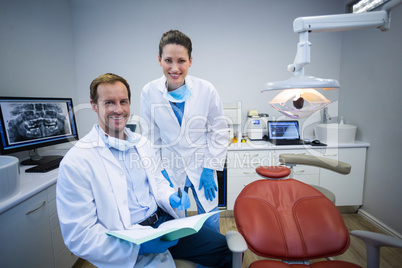 Portrait of smiling dentists holding medical report