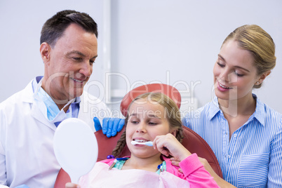 Dentist assisting young patient while brushing teeth