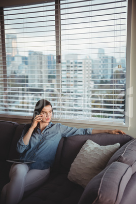 Woman talking on mobile phone while sitting on sofa