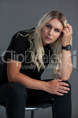 Beautiful transgender woman sitting on chair over gray background