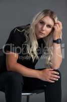 Beautiful transgender woman sitting on chair over gray background